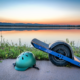 A Onewheel sits on the sidewalk next to a lake at sunset.